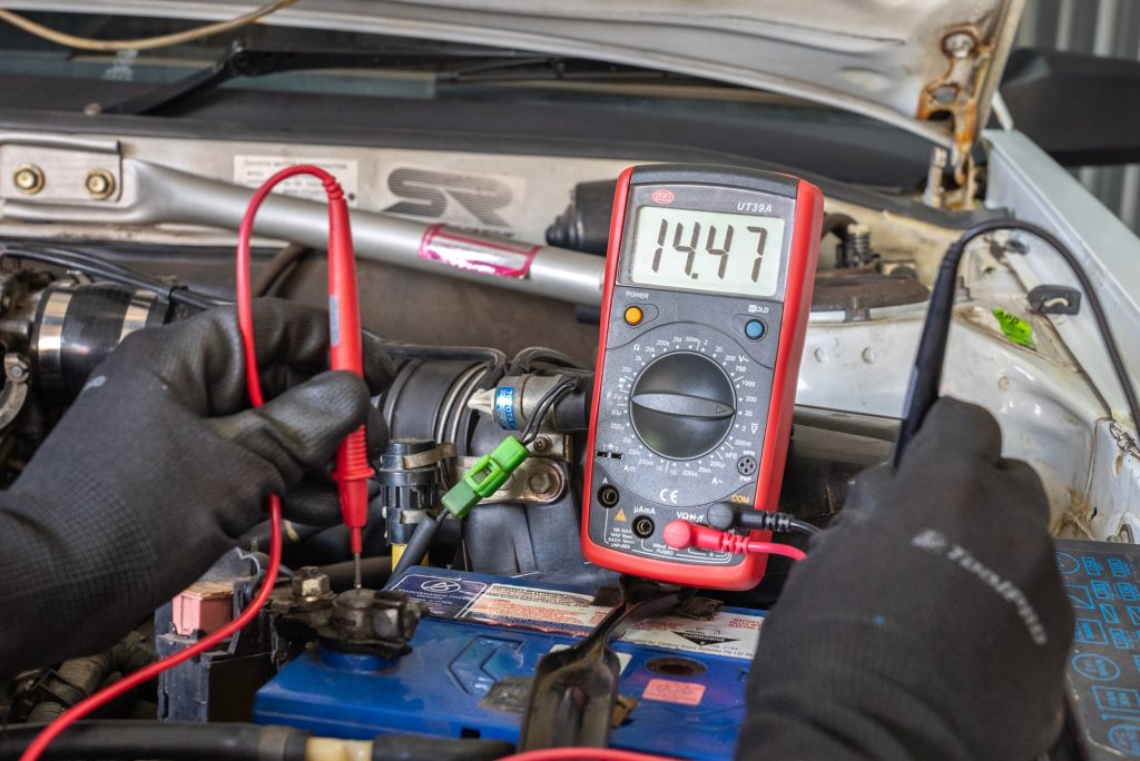 La batterie de la voiture est testée avec un multimètre ou démarrée à l'aide de câbles de démarrage.