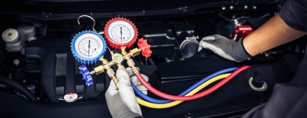 Un mécanicien vérifie les composants du système de climatisation sous le capot.