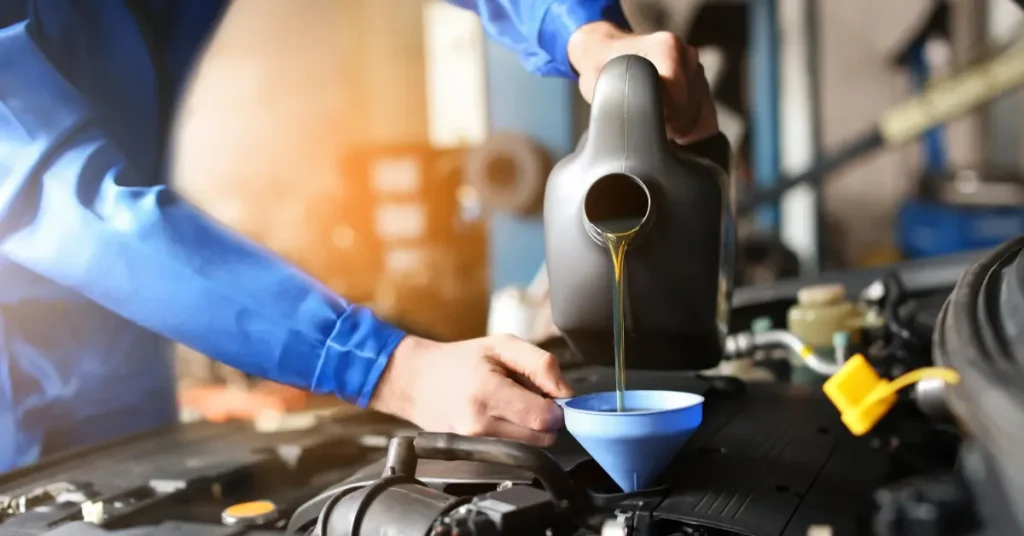 Un mécanicien effectue une vidange d'huile ou verse de l'huile de qualité dans le moteur. Vidange d'huile professionnelle avec huile synthétique de haute qualité.